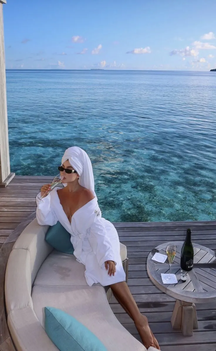 Mujer relajándose en una terraza frente al mar turquesa